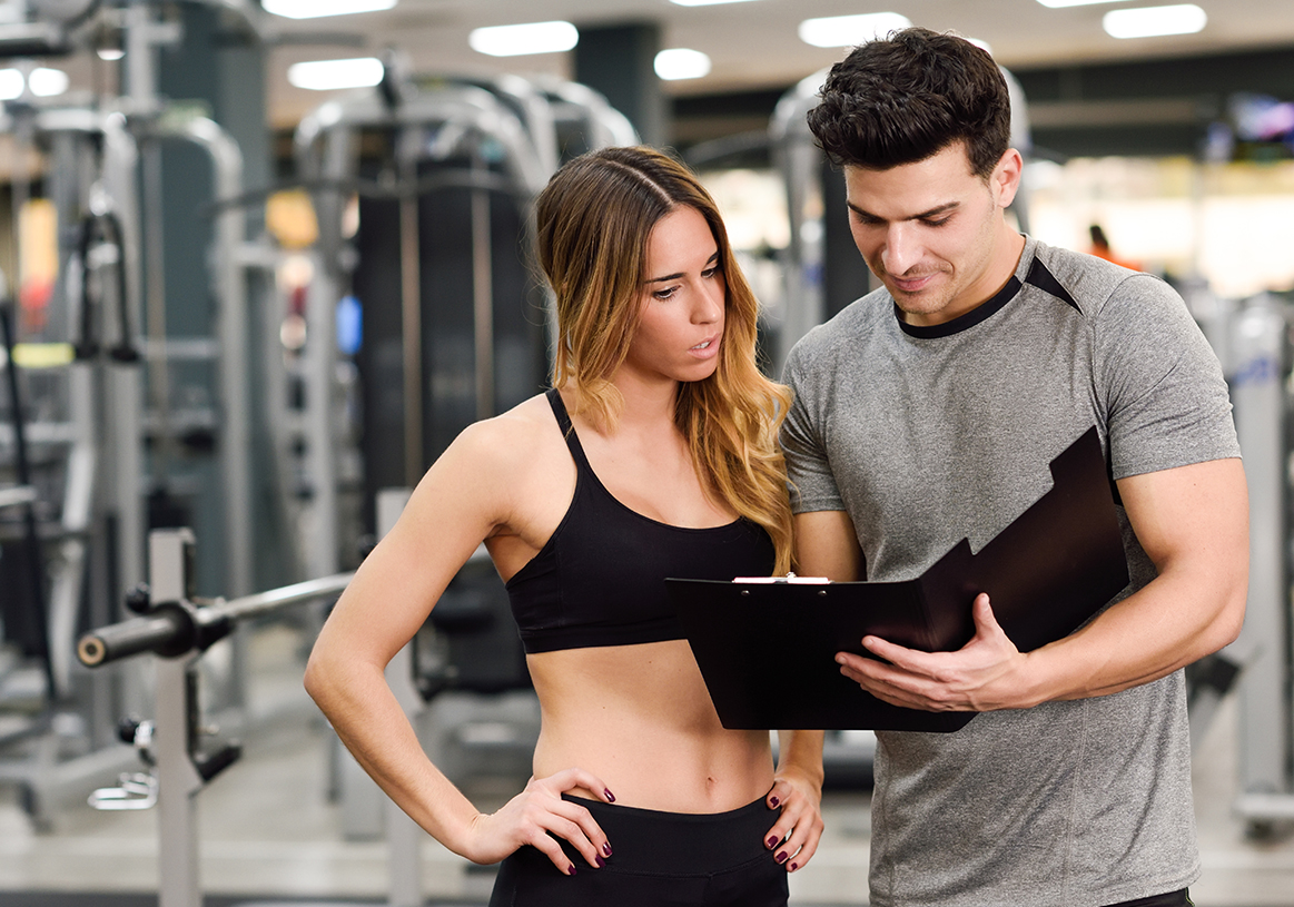Personal trainer and client looking at her progress at the gym